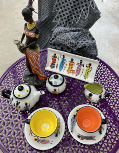 Decorative teapot, teacups and handcrafted ornaments displayed on a purple garden table at Teatrick Lavender Estate gift shop.