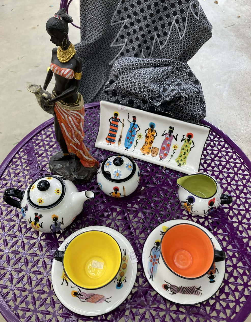 Decorative teapot, teacups and handcrafted ornaments displayed on a purple garden table at Teatrick Lavender Estate gift shop.