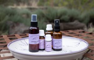 Teatrick Lavender Estate lavender water and lavender essential oil products displayed on a decorative tray outdoors.